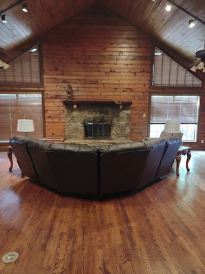 A room with a stone fireplace, wooden walls, and a leather sofa. - Spacious 4-bedroom house in charming Athens with AC (Athens)