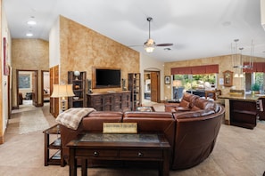 A spacious living room with a leather sofa, a television, and a fireplace. - Pool, Spa & Game Patio Oasis in Indian Wells (Indian Wells)