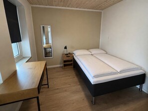 A bedroom with a bed, a bedside table, a lamp, a mirror, and a window. - Klaksvik Mountain View Stay (Klaksvík)