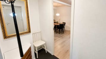 A hallway with a white radiator, a white chair, and a dining area with a table and chairs.