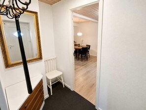 A hallway with a white radiator, a white chair, and a dining area with a table and chairs.