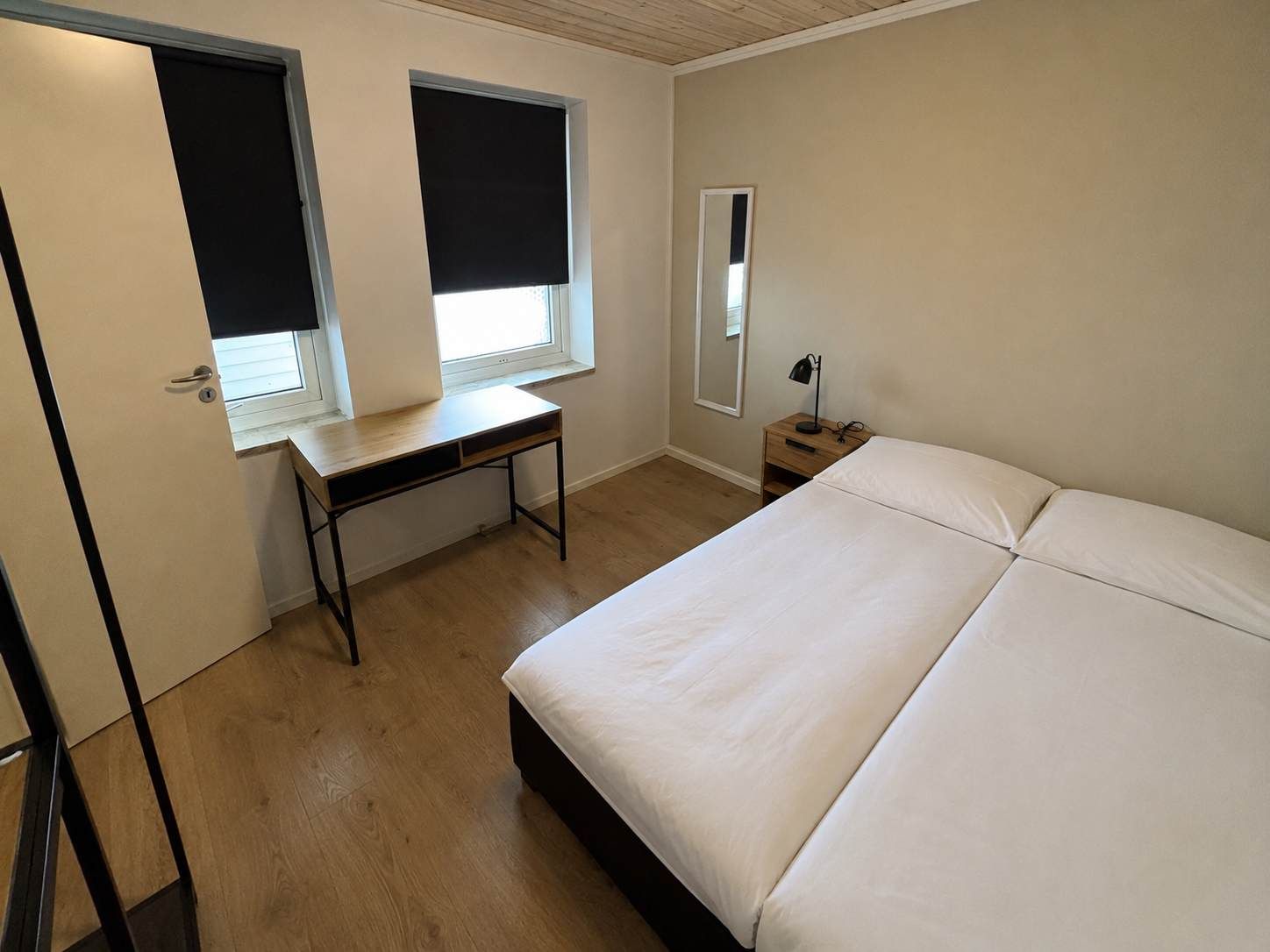 Ein Schlafzimmer mit einem Bett, einem Schreibtisch und einem Nachttisch.