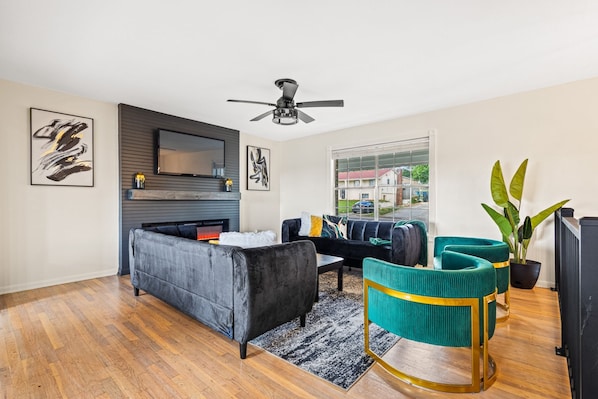A modern living room with a sofa, chairs, a fireplace, and a television. - Group Getaway- Theater Room + Game Room (Forest Park)