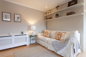A modern living room with a white sofa, patterned rug, and decorative items on shelves. -  Comfortable Apartments in Kensington by Short Stories London (London)