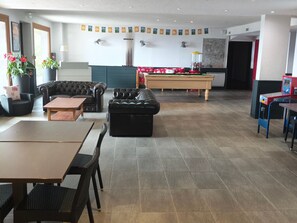 A room with a pool table, leather sofas, a dining table with chairs, and a ping pong table. - Bright apartment - 4 guests south view (Besse-et-Saint-Anastaise-Super Besse)