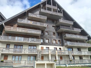 Een meerlaags gebouw met balkons, een stenen zuil en een heldere lucht.