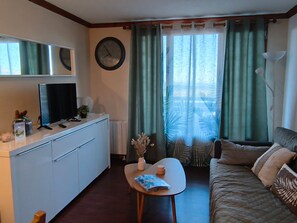 A compact room with a kitchenette, a bed, a small table with a vase, and a clock on the wall. - Bright apartment - 4 guests south view (Besse-et-Saint-Anastaise-Super Besse)
