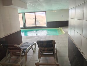 An indoor swimming pool area with tiled walls and a view of a desert landscape through large windows. - Bright apartment - 4 guests south view (Besse-et-Saint-Anastaise-Super Besse)