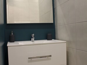 Ein Badezimmer mit einem weißen Waschbecken, einem Spiegel darüber und zwei schwarzen Seifenspendern.