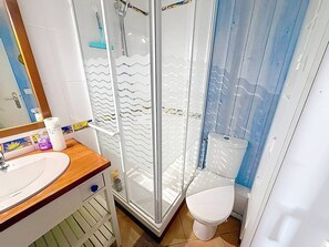 Ein Badezimmer mit Duschkabine, Toilette und Waschbecken mit Spiegel.