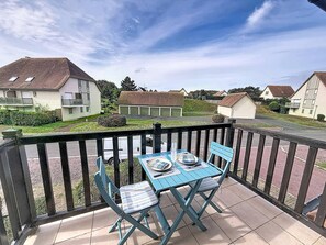 Ein Balkon mit Tisch und Stühlen, mit Blick auf ein Wohngebiet mit Häusern und einer Straße.