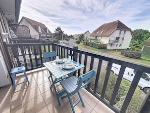 Ein Balkon mit einem Tisch für zwei Personen, Stühlen und Blick auf eine Wohnstraße.