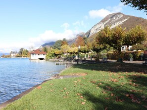 A lakeside view with a grassy area, benches, and a building with a red roof. - 50m² apartment, lake view - 2 guests (Veyrier-du-Lac)