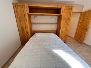A bedroom with a bed, wooden wardrobe, and a door. - Modern apartment - 4 guests (Vars)