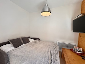 A bedroom with a bed, a bedside table, a TV, and a hanging light fixture. - Modern apartment - 4 guests (Vars)