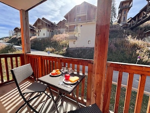 A wooden deck with a table set for two, overlooking a row of buildings. - Modern apartment - 4 guests (Vars)