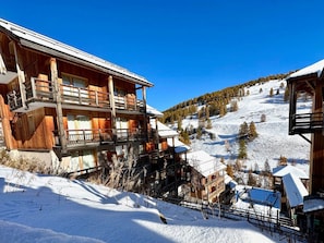 A wooden chalet with multiple balconies, set against a snowy mountain backdrop. - Modern apartment - 4 guests (Vars)