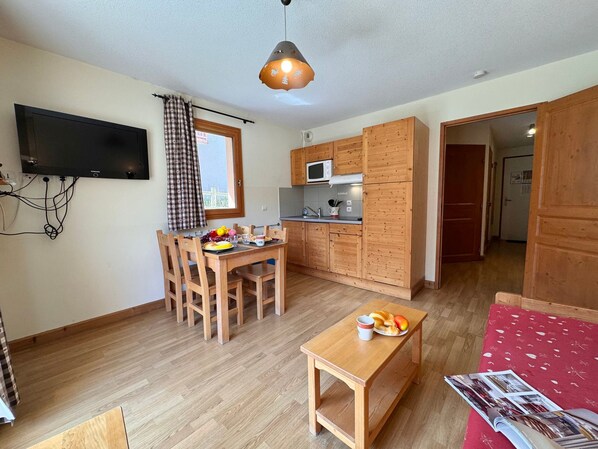 Une cuisine de taille réduite, avec des meubles de rangement en bois, une table à manger et des chaises.
