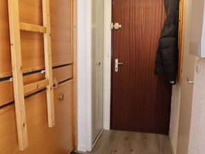 A wooden wardrobe with multiple compartments, a wooden door, and a coat hanging on the wall. - Bright studio - 4 guests, near ski lift (Saint-François-Longchamp)