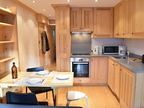 A compact kitchen with wooden cabinets, a Bosch oven, a microwave, and a coffee maker. - Apartment with mountain view - 4 guests (Méribel)