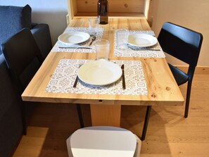 Ein Esstisch ist gedeckt mit Tellern, Besteck und Gläsern, umgeben von Stühlen.