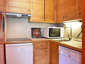 Una cucina compatta con mobili in legno, un forno a microonde, una lavastoviglie e un piccolo piano di lavoro.