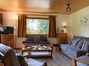 A cozy living room with a sofa, a coffee table, and a television. - Bright apartment, panoramic view - 6 guests (Méribel)