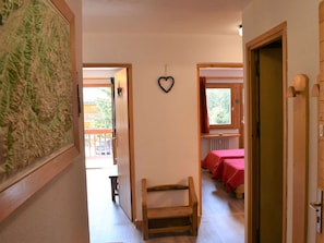 A hallway with a wooden bench, a heart-shaped decoration on the wall, and a view of a balcony with a red tablecloth. - Bright apartment, panoramic view - 6 guests (Méribel)