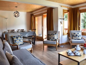 A cozy room with a dining area, two armchairs, a sofa, and a table set for tea. - Bright apartment, panoramic view - 6 guests (Méribel)