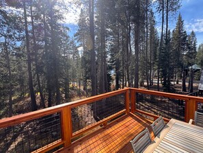 A wooden deck with a metal railing overlooking a forested area. - Beautiful 3BR Lakeview | 2 Living Rooms | Hot Tub (Soda Springs)