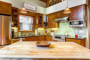 A kitchen with wooden cabinets, a stainless steel refrigerator, a microwave, a stove, and a large island with a basket. - Beautiful 3BR Lakeview | 2 Living Rooms | Hot Tub (Soda Springs)