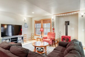 A living room with a flat-screen TV, a red armchair, a sofa, a coffee table, and a fireplace. - Beautiful 3BR Lakeview | 2 Living Rooms | Hot Tub (Soda Springs)