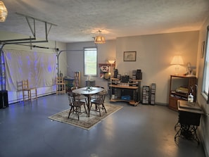 Una habitación con una mesa redonda, sillas, una estantería, una lámpara y un ventanal.