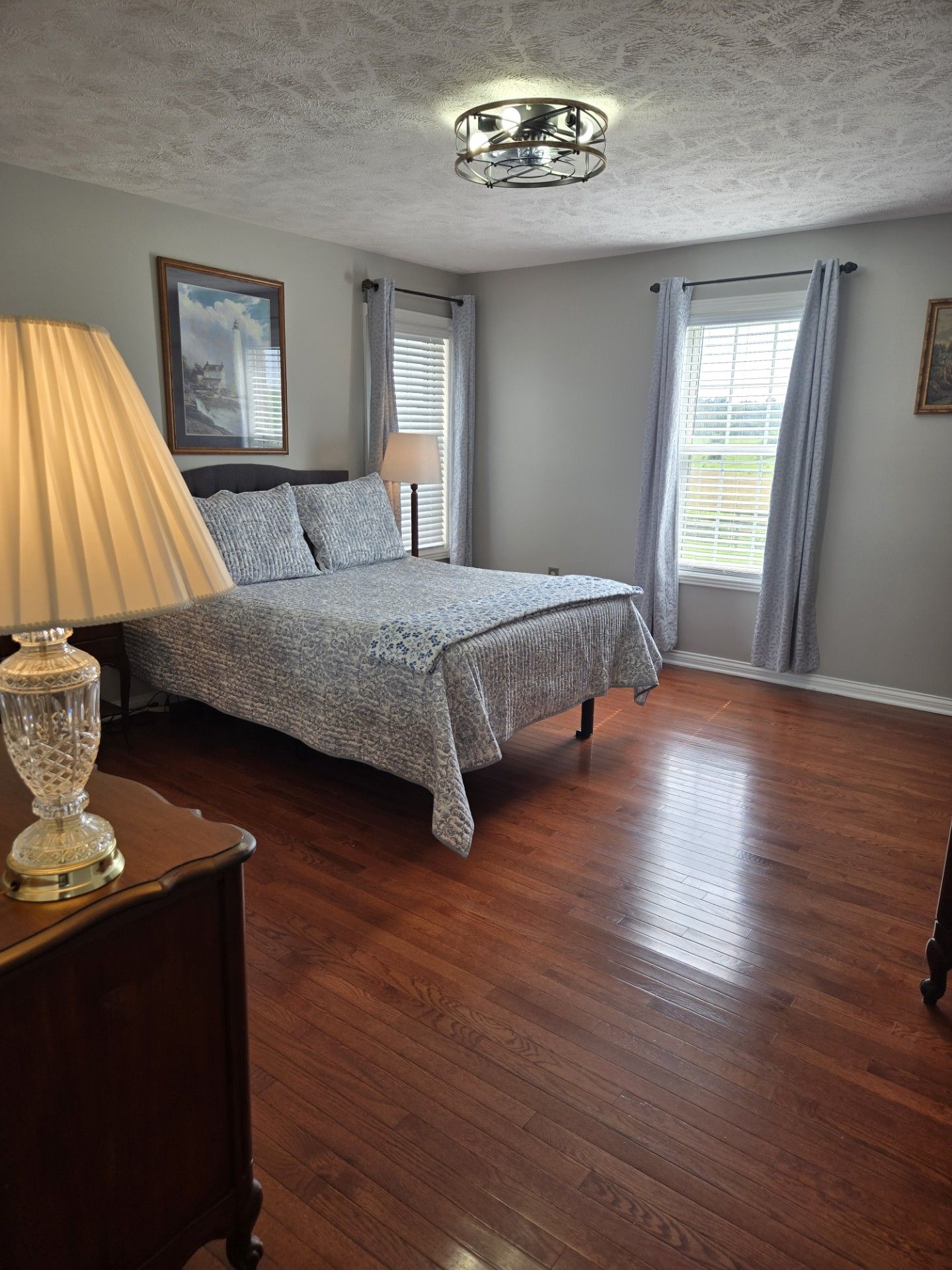 A bedroom with a bed, a nightstand, a lamp, and a ceiling light fixture.