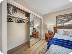 Ein Schlafzimmer mit einem Bett, Nachttischen, einem Kleiderschrank und einem Spiegel.