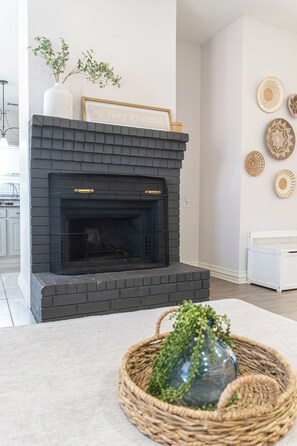 A modern living room with a black brick fireplace, a white sofa, and decorative wall art. - Spacious Arlington 5BR Sleeps 12 Near AT&T Stadium & Stovall Park (Arlington)