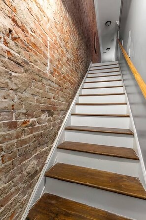 Un escalier avec des marches en bois et un mur en briques.