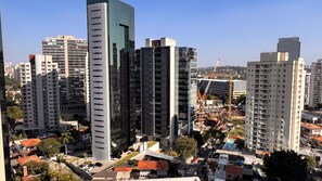 A high-rise building with a modern design, surrounded by other tall buildings and construction cranes. - Studio Nex One Faria Lima - A 3 min do Metrô (São Paulo)