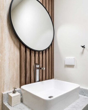 Een moderne badkamer met een vrijstaand bad, een ronde spiegel en een wandpaneel van hout.