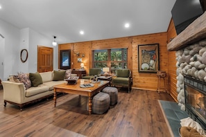 A cozy living room with a wooden floor, a sofa, a coffee table, and a fireplace.