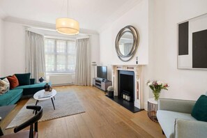 Ein modernes Wohnzimmer mit Kamin, Fernseher und einer Couch.