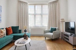 Ein modernes Wohnzimmer mit einer Couch, einem Sessel, einem Couchtisch und einem Fernseher.