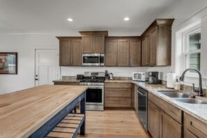 Una cocina moderna con armarios de madera, electrodomésticos de acero inoxidable y una mesa de comedor de madera.