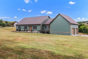 A two-story house with a front porch, a garage, and a well-maintained lawn. - Magical Family Escape: Treehouse, Games, Memories (Spring Hill)