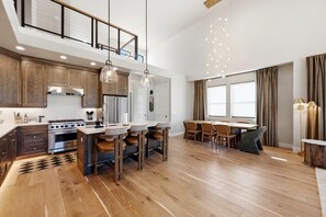 A modern kitchen with a central island, wooden cabinets, and stainless steel appliances. - brand new townhome across the road from the East Village/ Grand Hyatt Area (Heber City)
