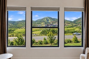 A room with three windows overlooking a hilly landscape with a road and a building. - brand new townhome across the road from the East Village/ Grand Hyatt Area (Heber City)
