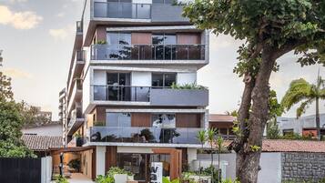 A multi-story residential building with balconies, a driveway, and a tree in the foreground.