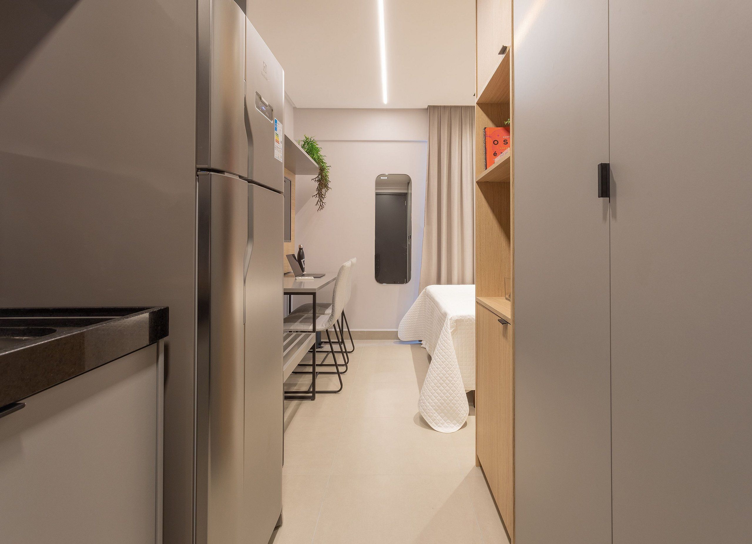 Una cocina compacta con refrigerador, una zona de comedor con mesa y sillas, y un ventanal con cortinas.