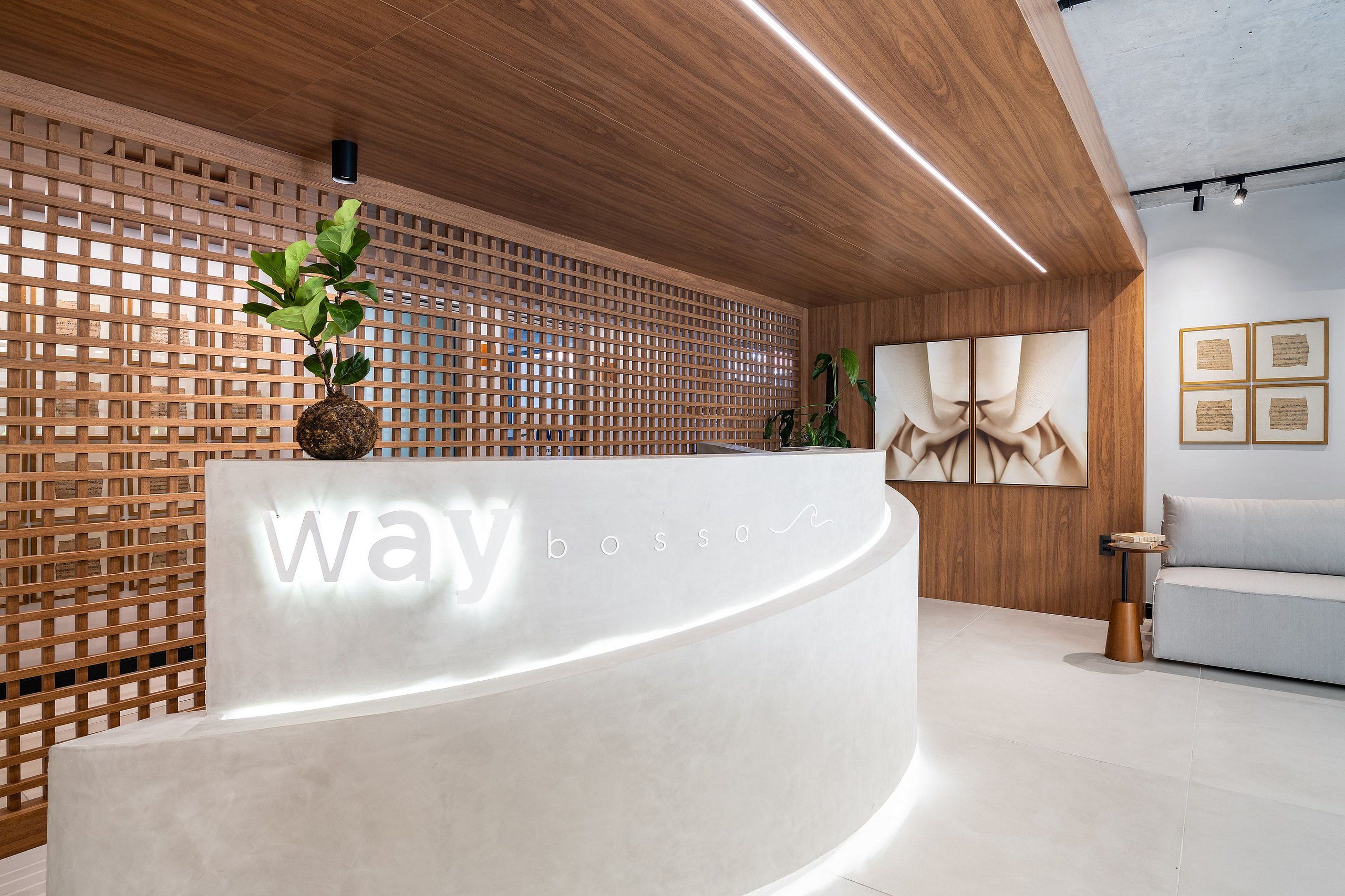 A reception desk with a wooden lattice wall, a potted plant, and framed artwork on the wall.