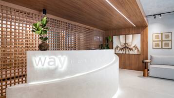 A reception desk with a wooden lattice wall, a potted plant, and framed artwork on the wall.